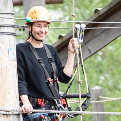 Junge Frau steht auf der Plattform eines Kletterelements